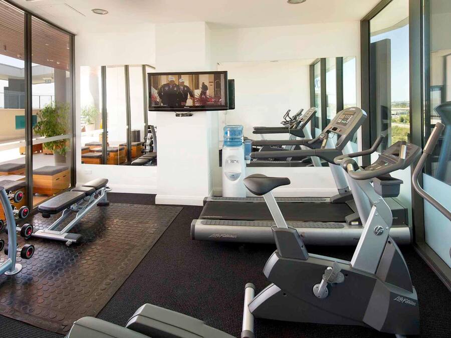 Una palestra moderna con tapis roulant, vogatore e attrezzature per sollevamento pesi.