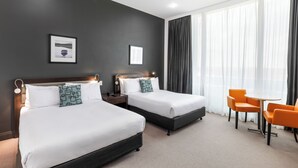 Une chambre d’hôtel avec deux lits, une petite table et des chaises.