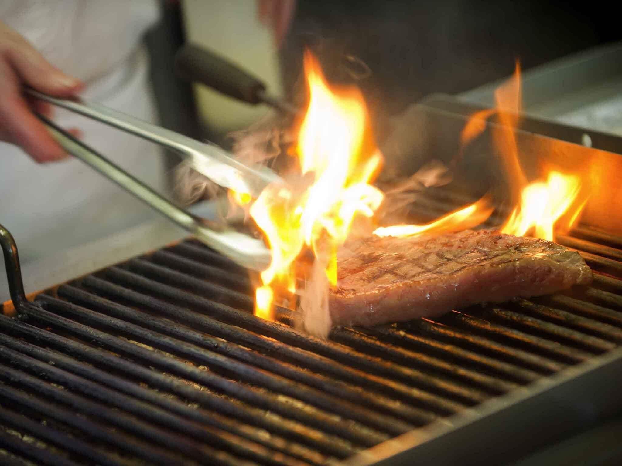 Un steak grillé sur un barbecue, avec des flammes apparentes.