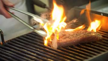 Un steak grillé sur un barbecue, avec des flammes apparentes.