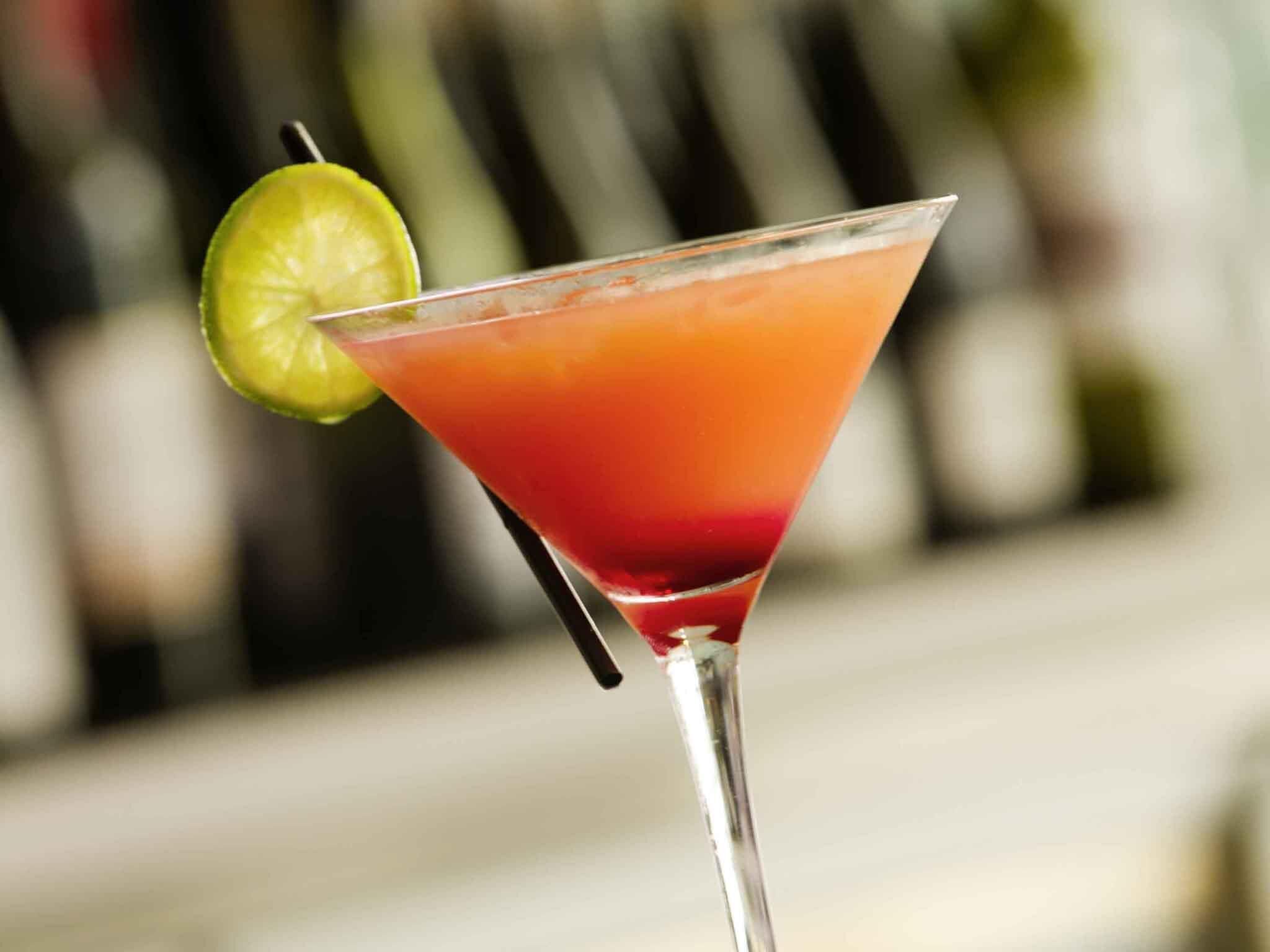 A cocktail in a martini glass with a lime garnish.