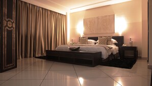 A modern bedroom with a large bed, a nightstand, and a wall-mounted artwork. - Oak Plaza Hotels - East Airport (Accra)