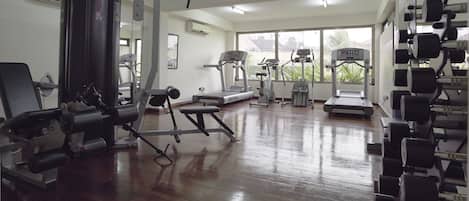 A gym with various exercise equipment, including treadmills, weight machines, and free weights.