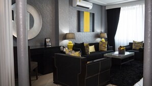 A modern living room with a black sofa, two side tables, a coffee table, and decorative pillows. - Oak Plaza Hotels - East Airport (Accra)