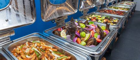 Un bufé con diversas opciones de comida, como pasta, ensaladas y platos de carne.