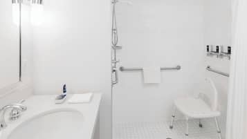 A bathroom with a white sink, mirror, and shower area.