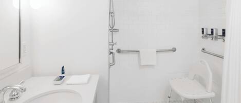 A bathroom with a white sink, mirror, and shower area.