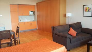 A compact living space with a kitchenette, a sofa, a dining table, and a bed.
