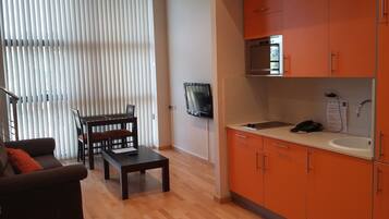 Un espacio habitable compacto con comedor, kitchenette y zona de estar con sofá y mesa.