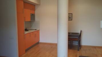 A kitchen with orange cabinets, a white countertop, and a wooden dining table with chairs.
