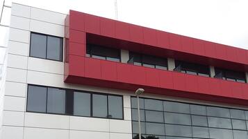 Un edificio moderno con fachada roja y blanca, ventanas amplias y techo plano.