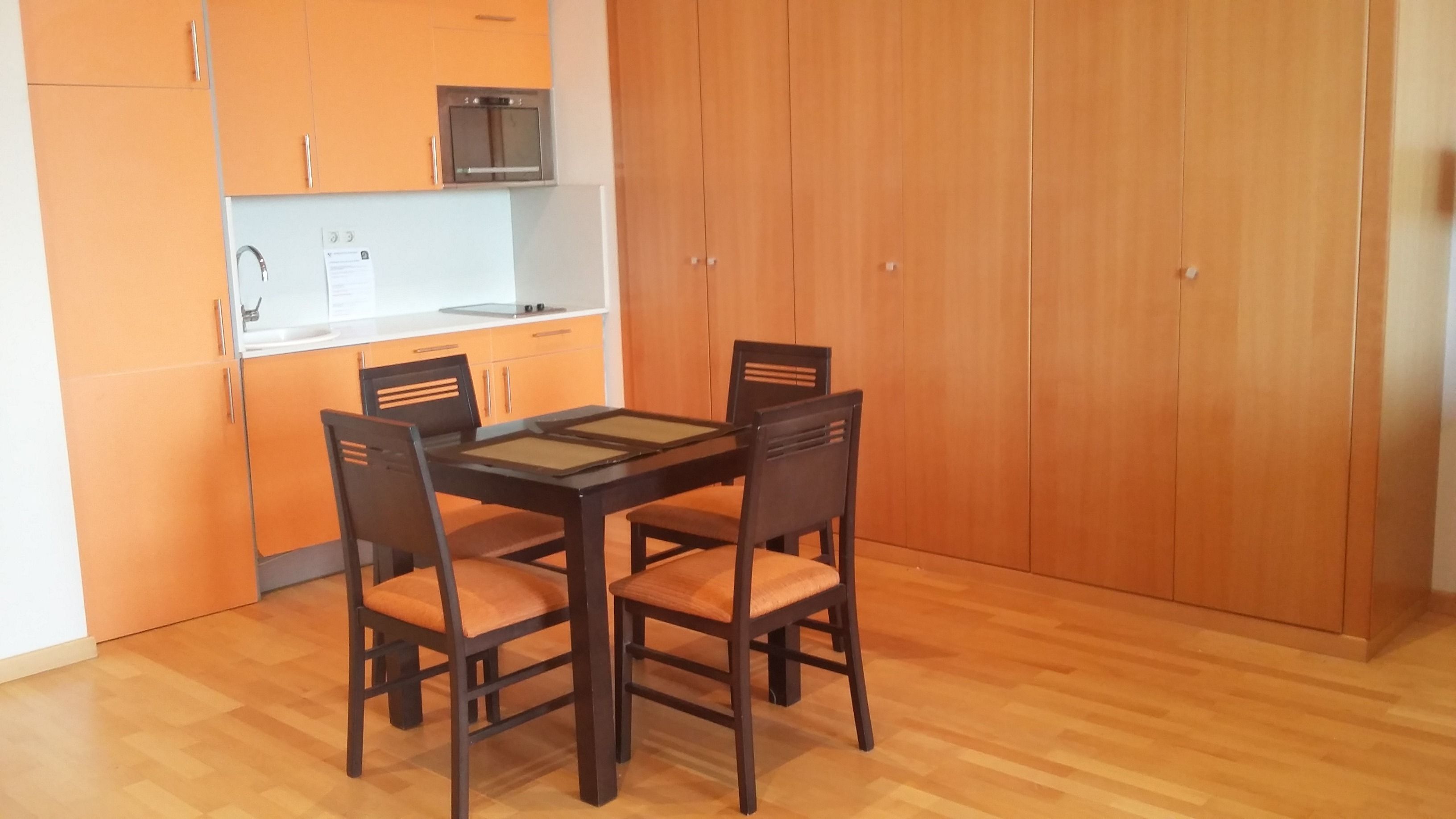 A compact kitchen with a microwave, a sink, and wooden cabinets.