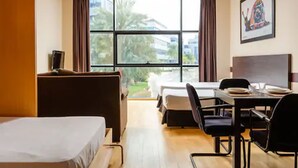 A hotel room with a bed, a desk, and a dining table. - Aparthotel Wellness (Paterna)