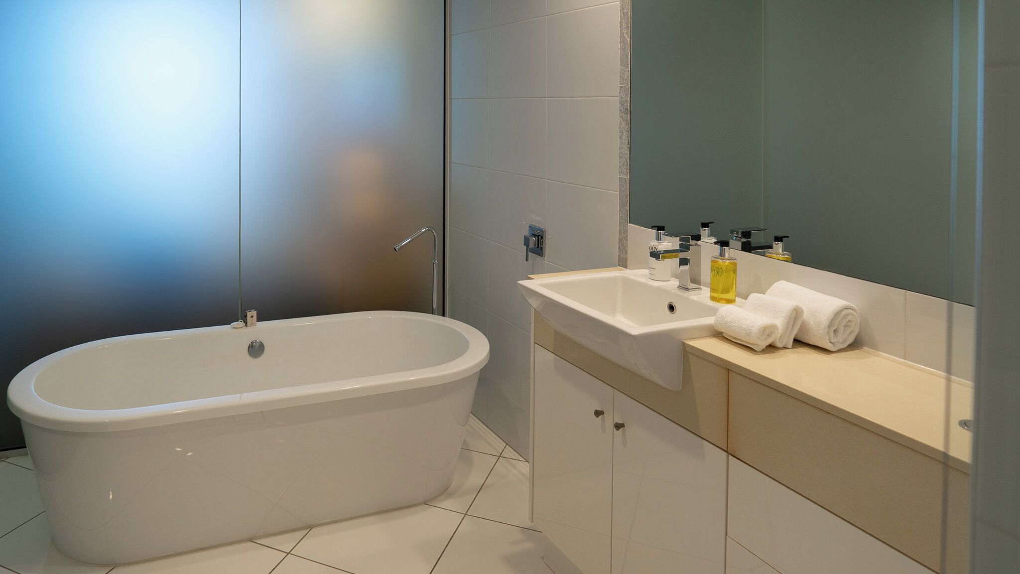 A modern bathroom with a freestanding bathtub, a vanity with a mirror, and toiletries.