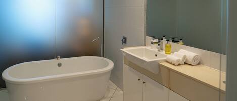 A modern bathroom with a freestanding bathtub, a vanity with a mirror, and toiletries.