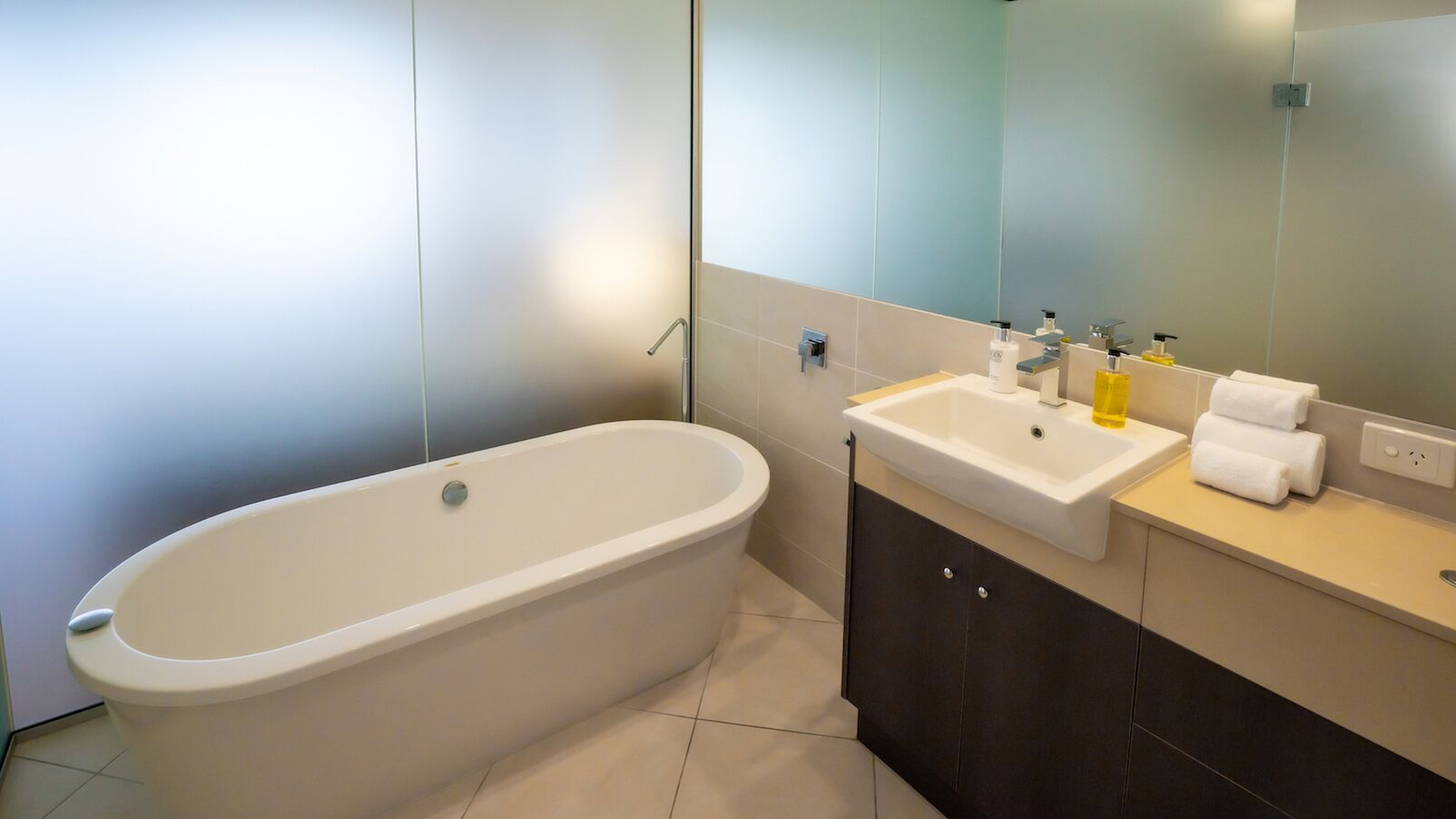 Une salle de bain moderne avec une baignoire sur pieds, un lavabo et un miroir.