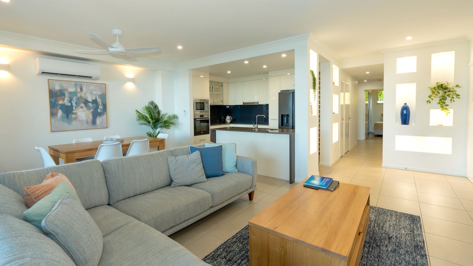 Una sala de estar moderna con un sofá gris, una mesa de centro de madera y un comedor con mesa y sillas.