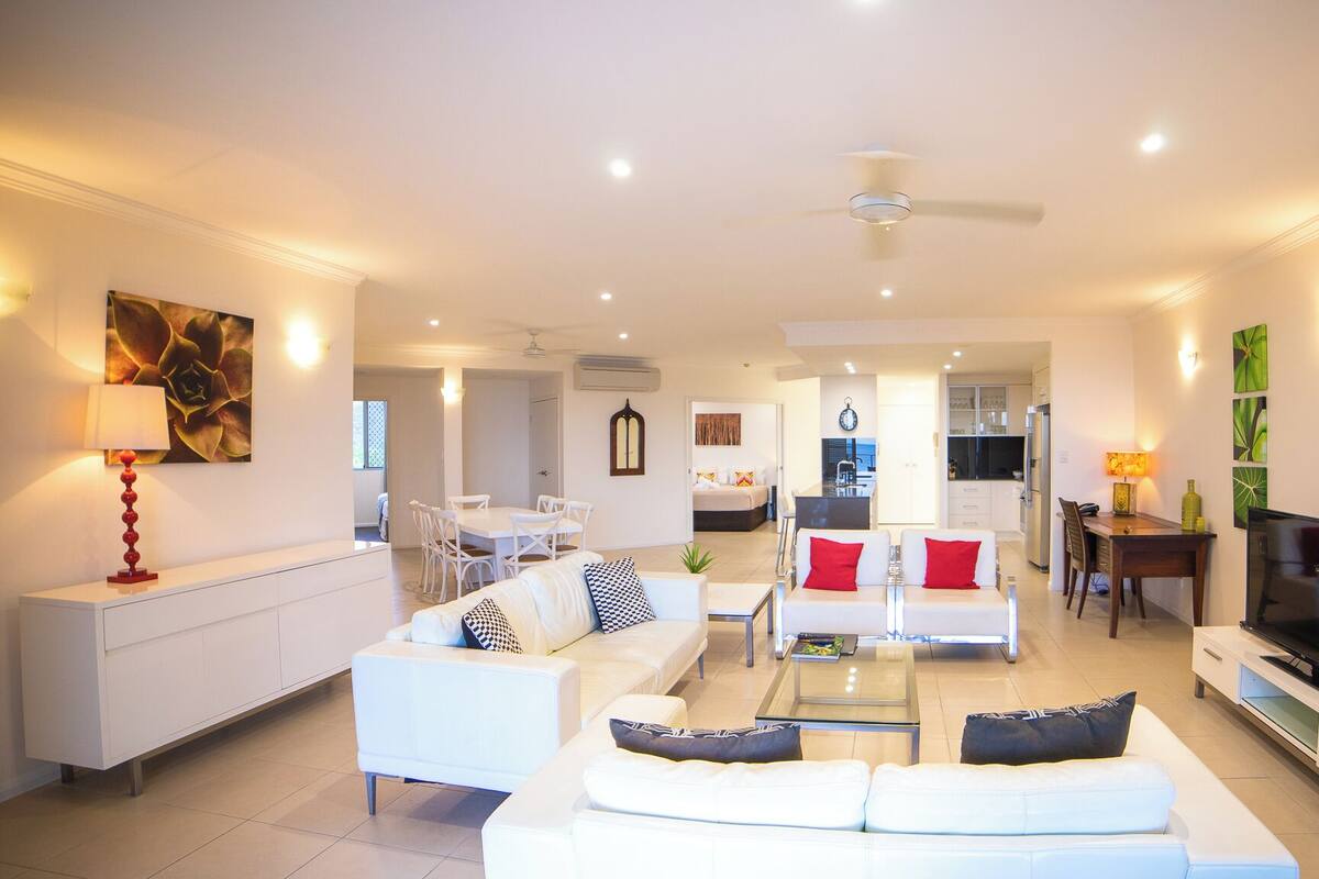 A modern living room with a sofa set, a dining table, and a TV.
