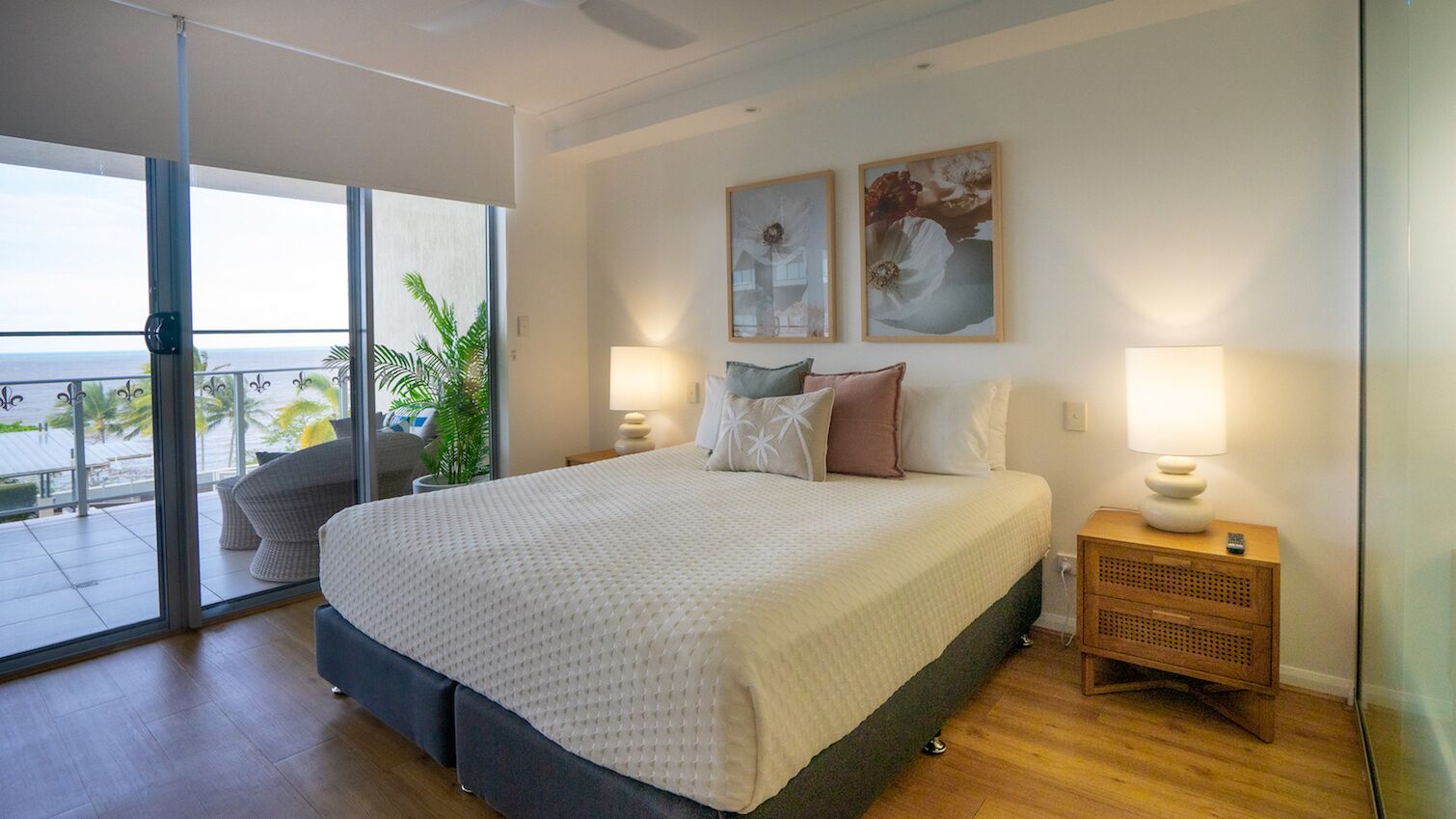 Ein Schlafzimmer mit einem großen Bett, zwei Nachttischlampen und Meerblick durch eine Glastür.