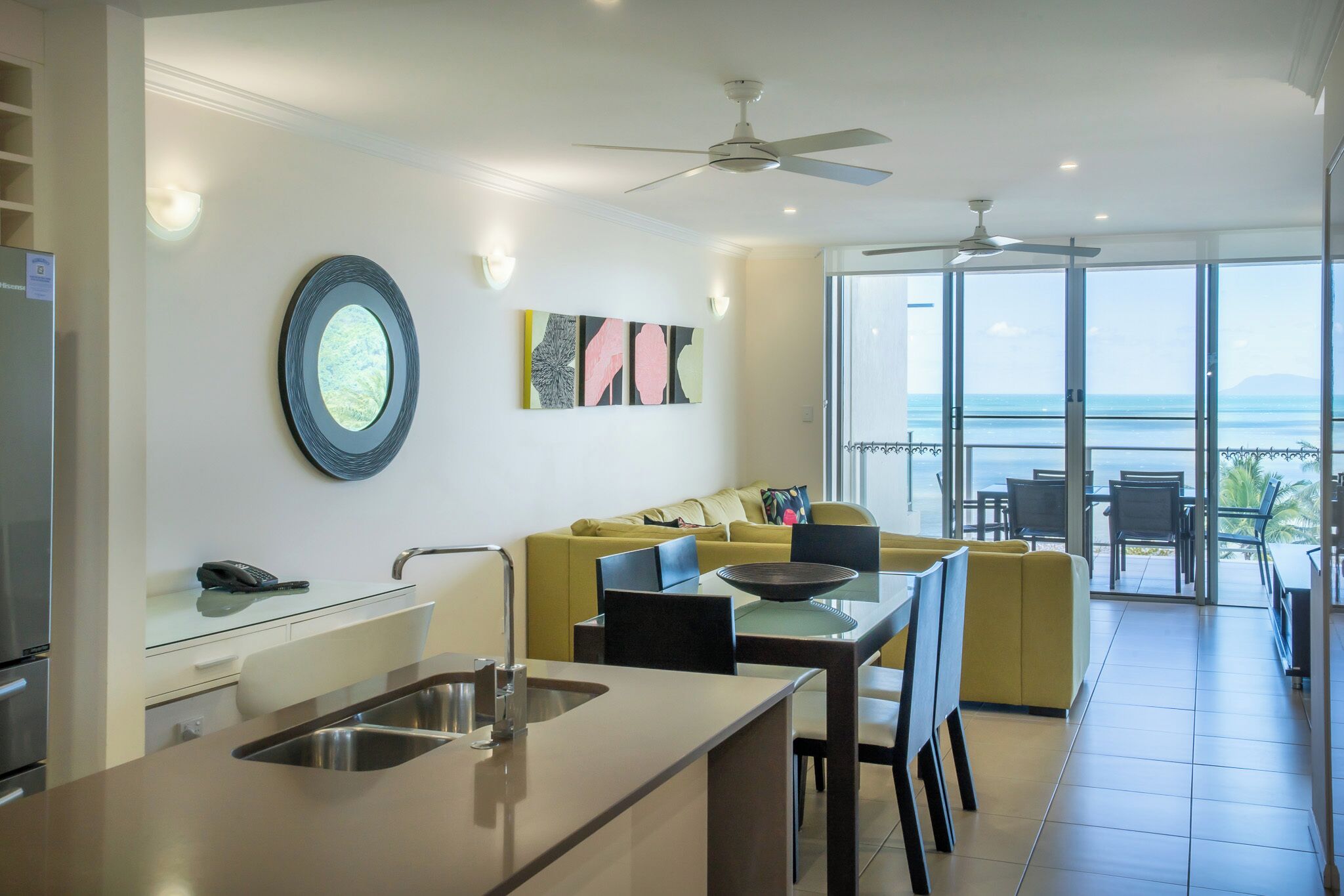 Una cocina moderna con comedor, un sofá amarillo y un balcón con vista al océano.
