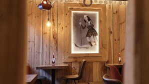 A wooden interior with a framed vintage photograph, a wooden table, and a chair. - Apartaments La Neu (Llorts)