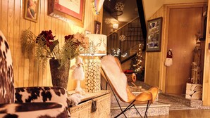 A cozy room with a wooden floor, a decorative lamp, a chair, and a staircase with a railing. - Apartaments La Neu (Llorts)