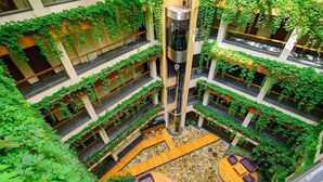 A multi-level atrium with greenery, a central elevator, and seating areas. - Boutique SPA Hotel Orchidea (Golden Sands)
