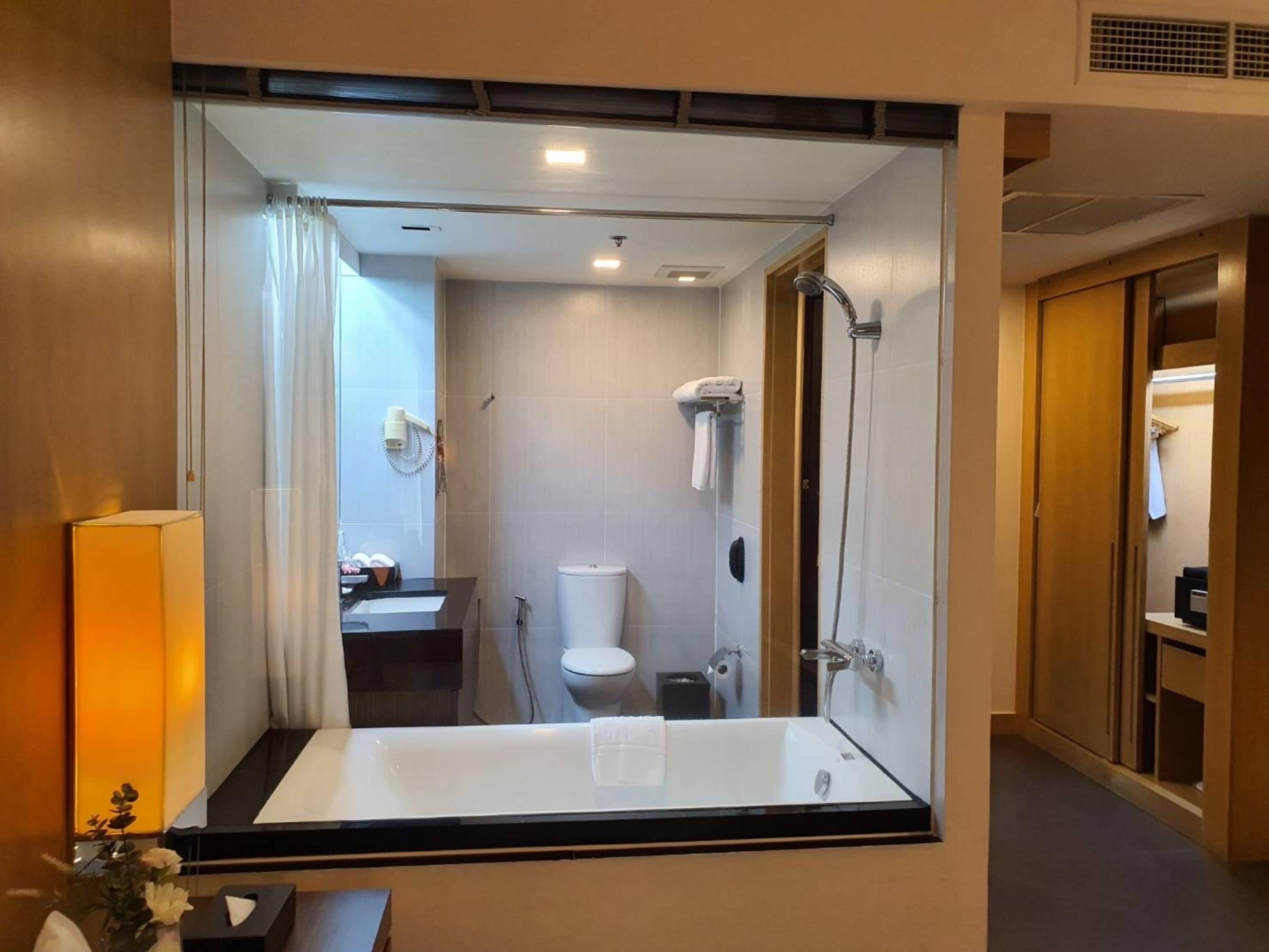 Une salle de bain moderne avec un grand miroir, une baignoire, une douche et des toilettes.