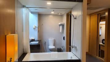 Une salle de bain moderne avec un grand miroir, une baignoire, une douche et des toilettes.