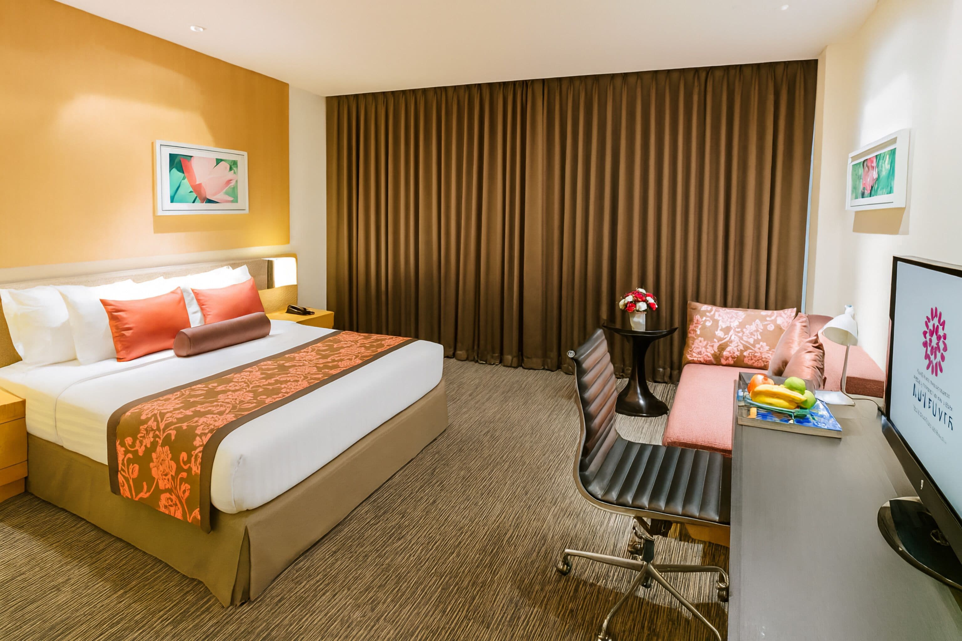 A hotel room with a bed, bedside table, desk, chair, and a television.