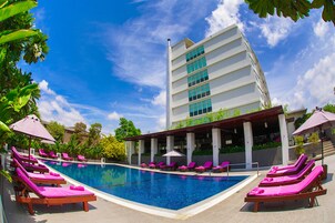 Una piscina al aire libre, sombrillas, sillones reclinables de piscina