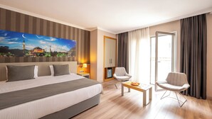 A hotel room with a large bed, a desk, two chairs, a painting of a mosque, and a view of the outdoors. - Klas Hotel Istanbul Old City (Istanbul)
