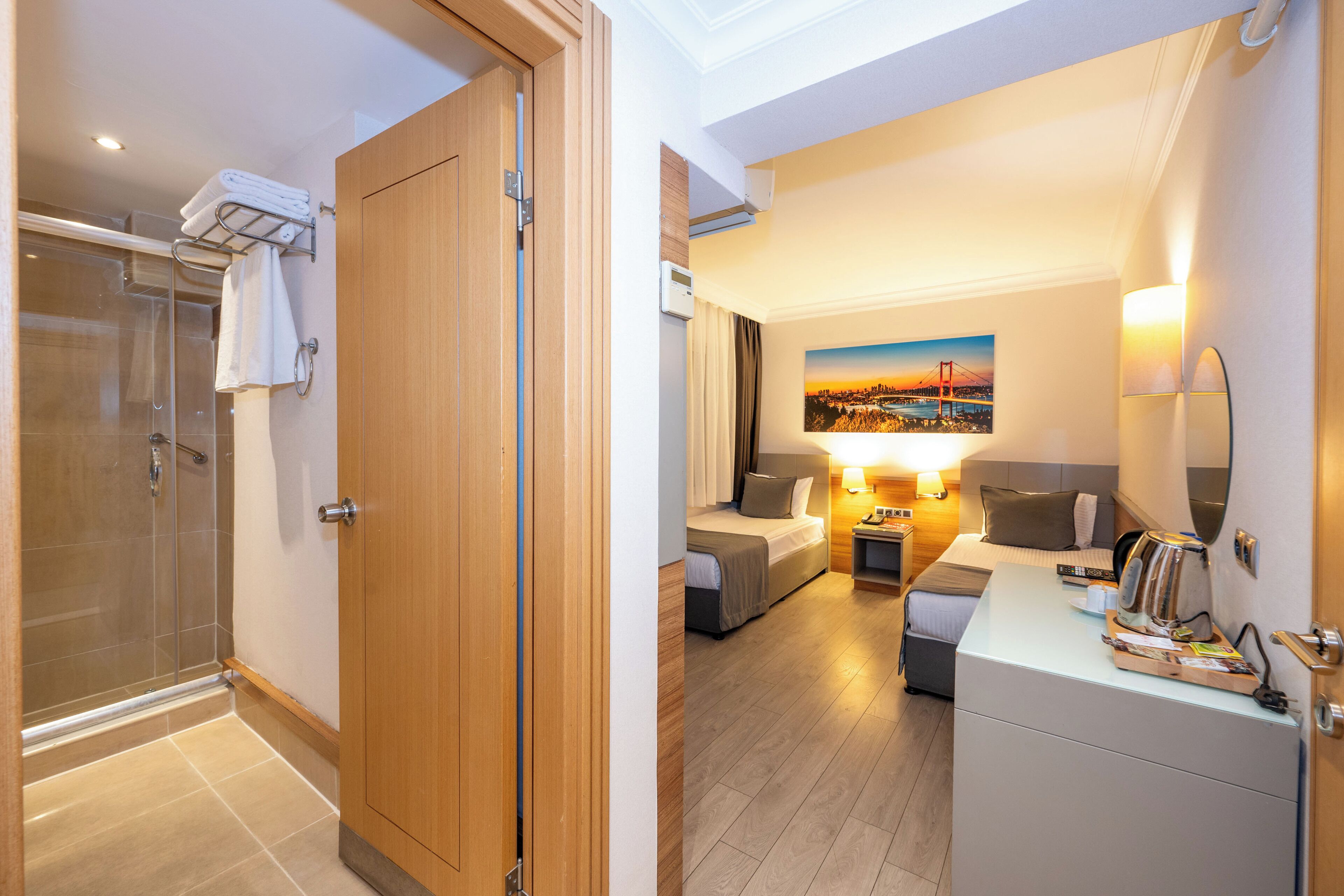 Une chambre d’hôtel avec une douche, un lit, un bureau et un tableau représentant un pont.