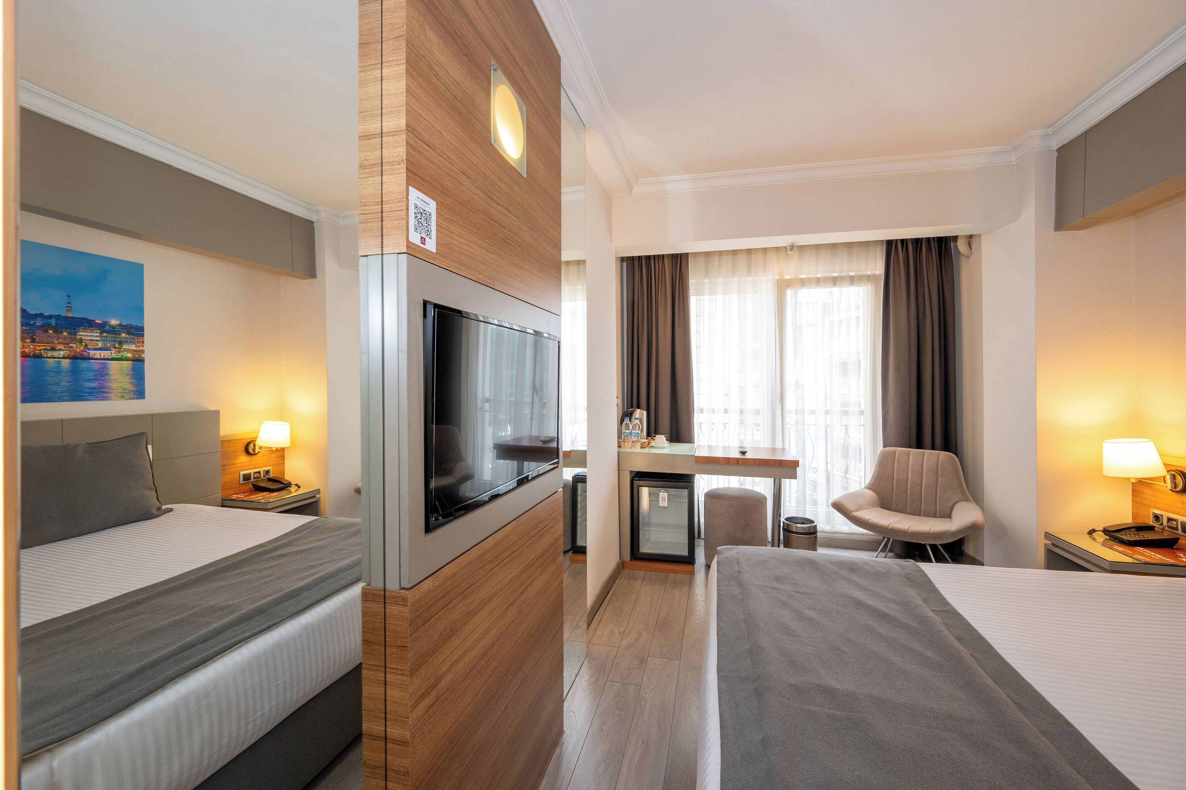 Une chambre d’hôtel avec deux lits, une télévision, un bureau, une chaise et un petit réfrigérateur.
