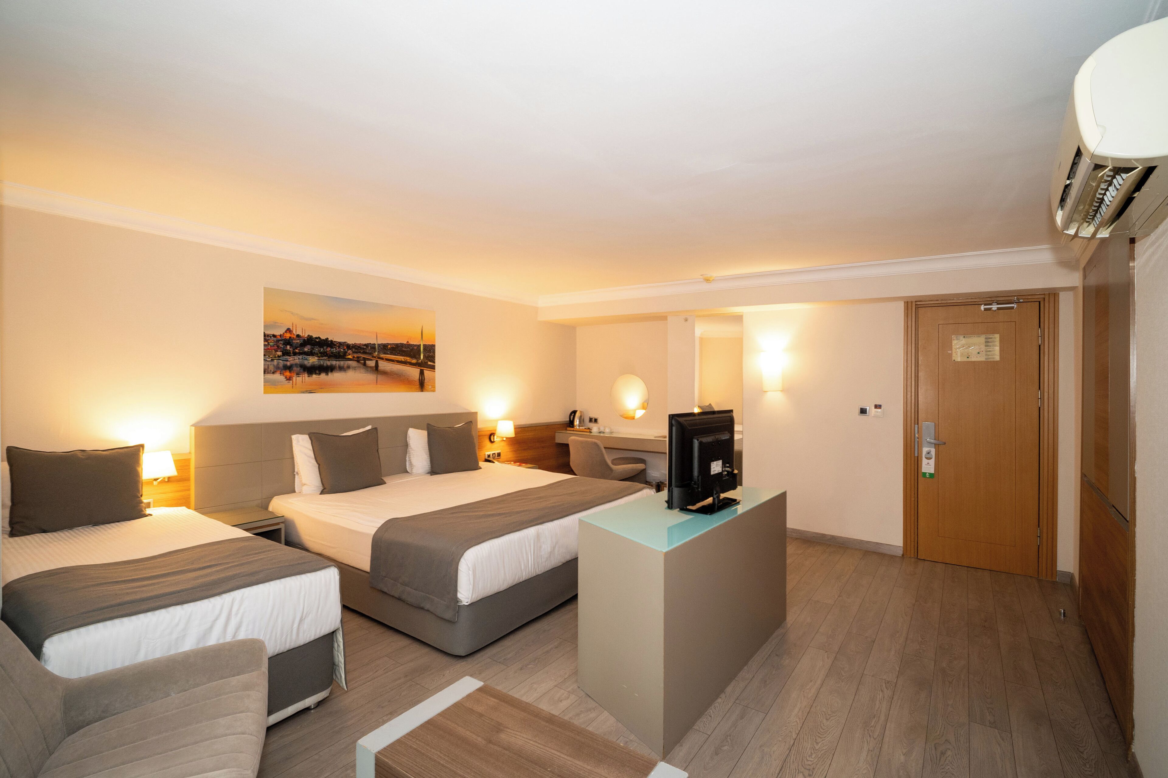 Une chambre d’hôtel avec deux lits, un bureau, une télévision et une vue sur le paysage urbain.