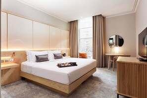 A modern hotel room with a large bed, bedside table, TV, and a desk with a chair. - The Prince Akatoki London (London)