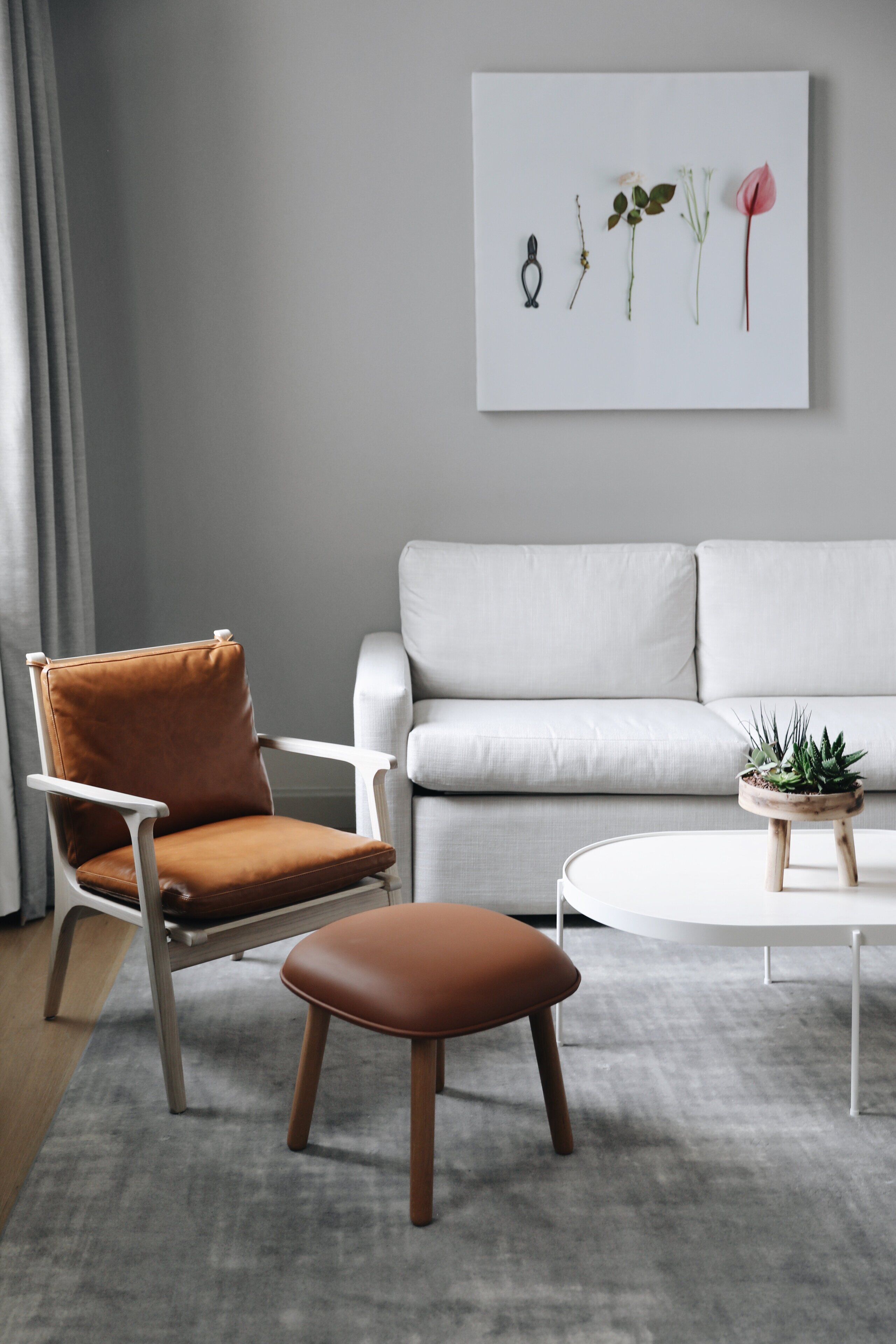 A modern living room with a brown leather chair, a white sofa, and a round coffee table with a small plant.