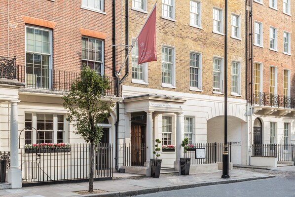 A row of traditional brick buildings with white facades, a prominent red flag, and a well-maintained sidewalk. - The Prince Akatoki London (London)