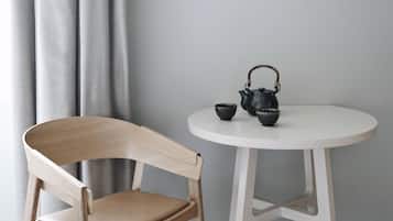 A wooden chair and a white table with a teapot and cups.
