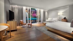 A modern hotel room with a large bed, a TV, a seating area with a table and chairs, and a view of a garden through the window. - The Prince Akatoki London (London)