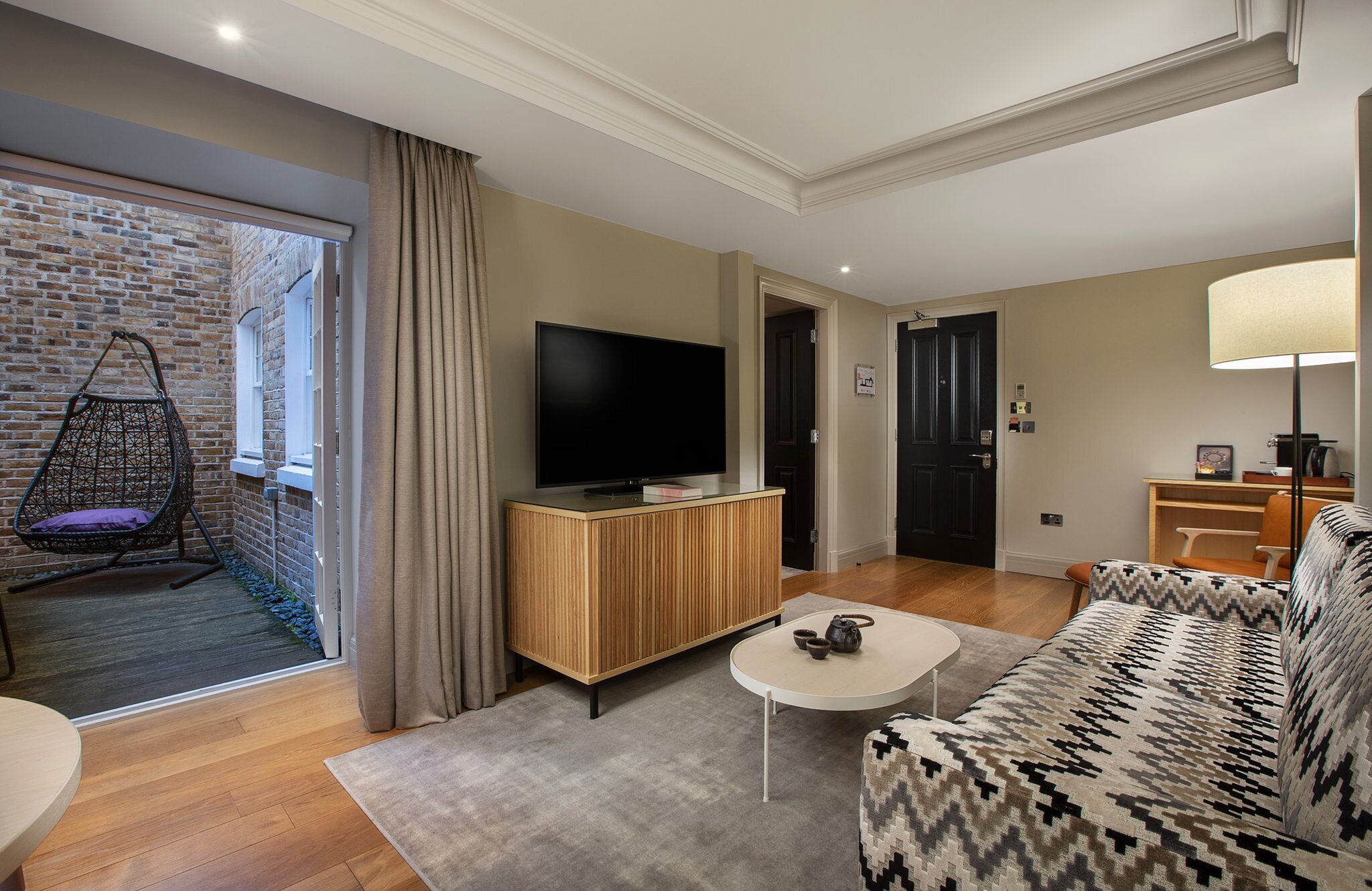 Ein modernes Wohnzimmer mit Fernseher, einer Couch, einem Couchtisch und einem Hängesessel.