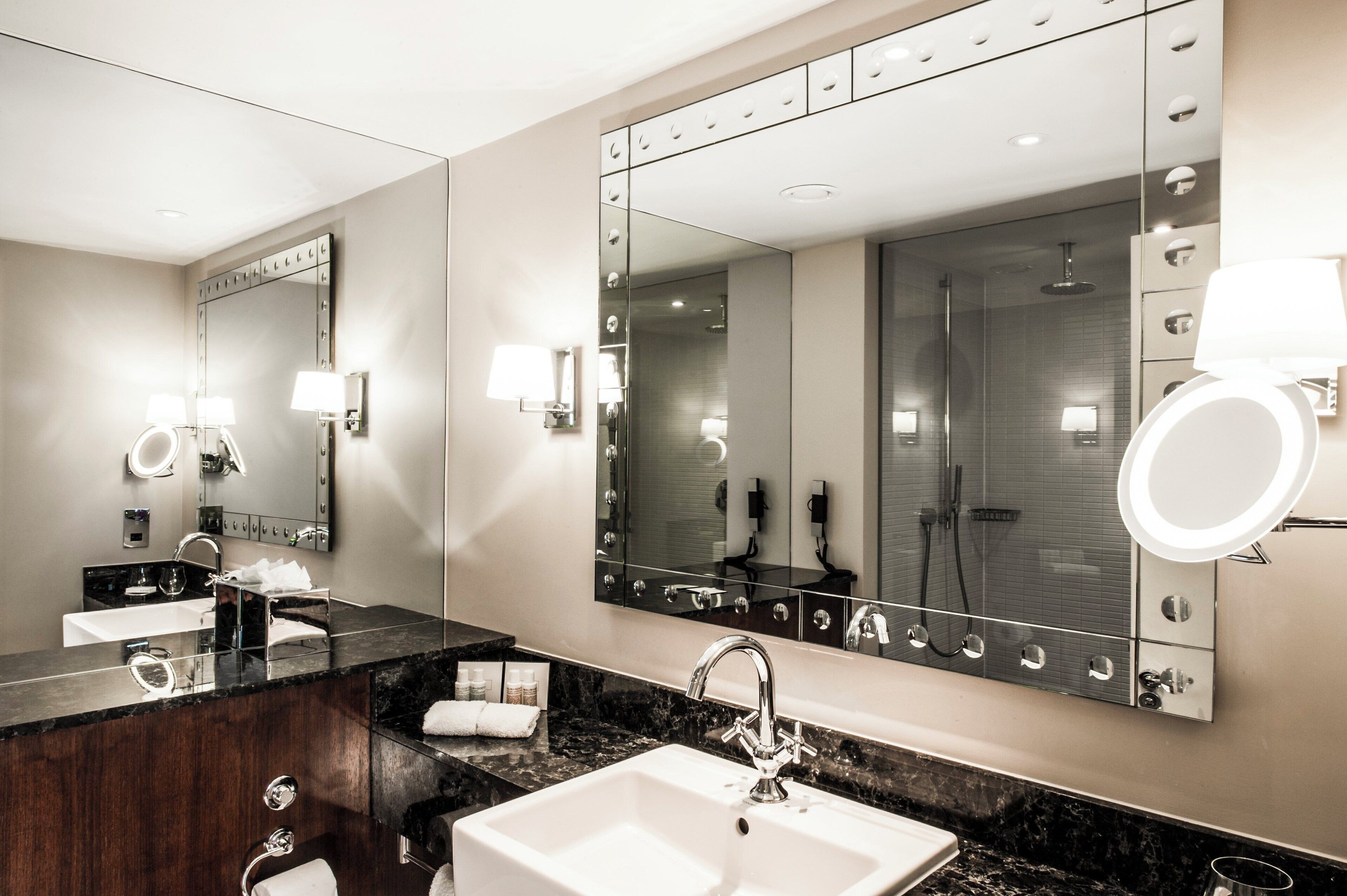 Un baño moderno con un espejo grande, dos lavamanos y una ducha.