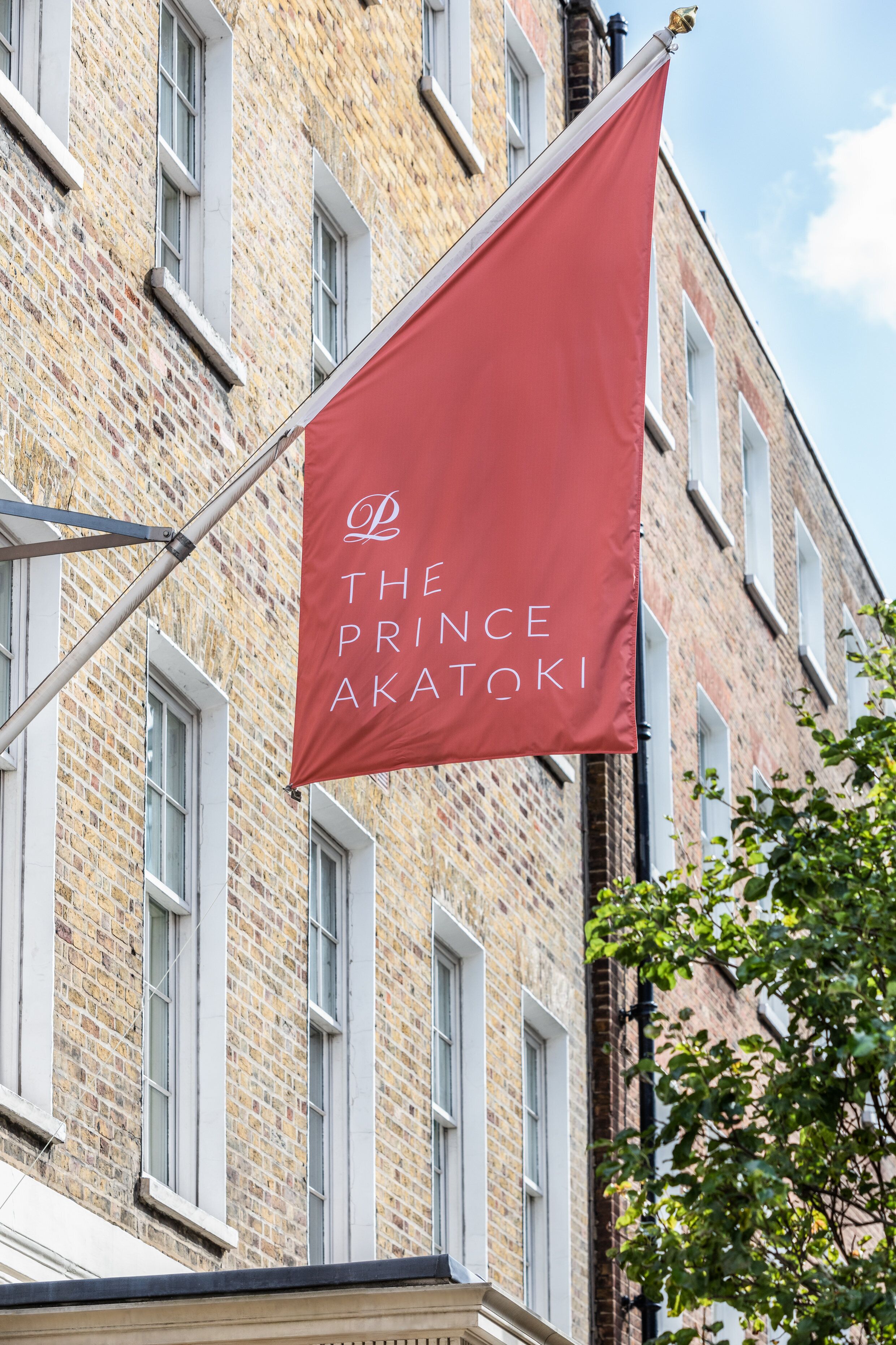 A red flag with white lettering hanging from a building's window.