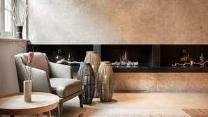 A modern living room with a fireplace, a beige sofa, and three decorative vases. - The Prince Akatoki London (London)