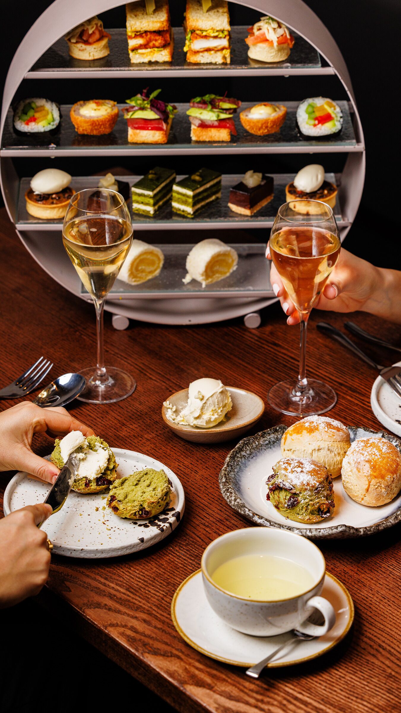 A dessert display with various pastries and a glass of white wine.