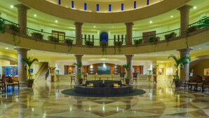 A multi-level hotel lobby with a central fountain, multiple balconies, and potted plants.