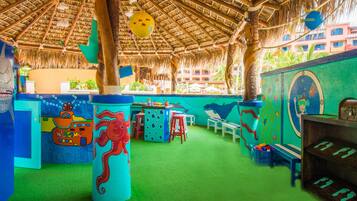 A colorful play area with a thatched roof, green flooring, and various play structures including a large octopus figure and a submarine.