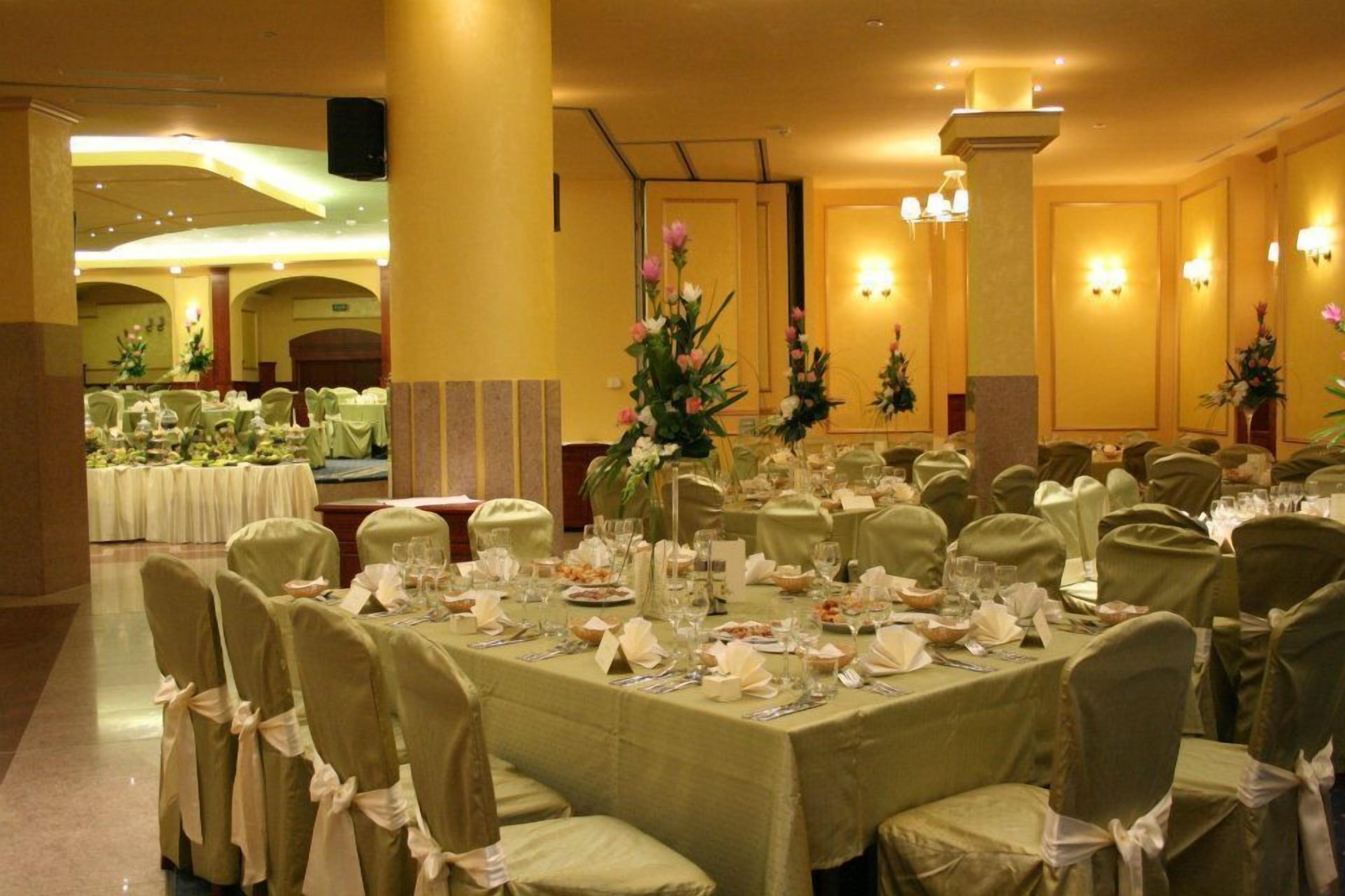 A banquet hall with round tables set for a formal event, featuring floral centerpieces and neatly arranged table settings.