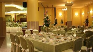 A banquet hall with round tables set for a formal event, featuring floral centerpieces and neatly arranged table settings.