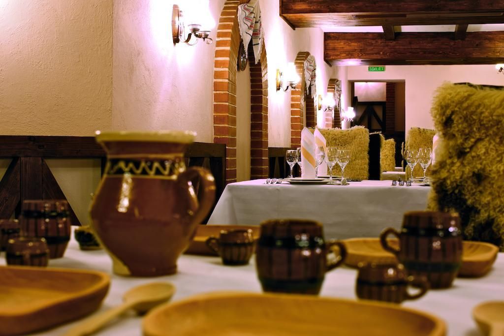 Un salón de restaurante con una mesa dispuesta para comer, incluyendo platos, tazas y un jarrón grande.